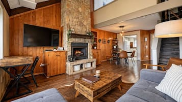 A spacious living area with a stone fireplace, wooden furniture, and a flat-screen TV.