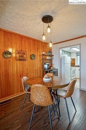 A wooden-paneled dining area with a round table, four chairs, and a ceiling light fixture. - The Beech Club ★ Breathtaking Views ★ Pet Friendly ★ (Beech Mountain)