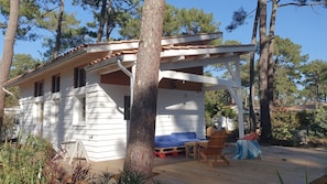 Uma cabana de madeira com varanda, um pequeno alpendre e um espaço coberto para sentar.