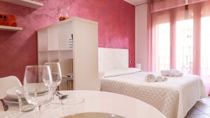 Une chambre d’hôtel avec un lit, une table à manger avec de la vaisselle et une tête de lit blanche.