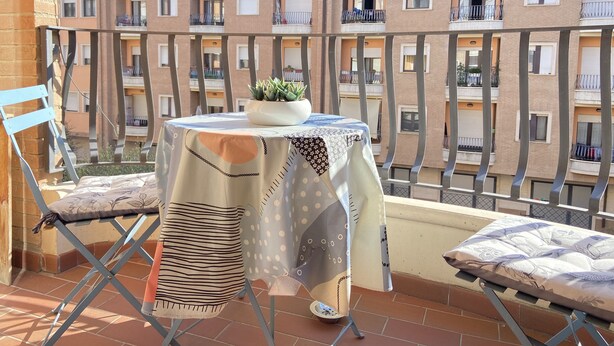 Un balcon avec une table, des chaises et un pot de fleurs.
