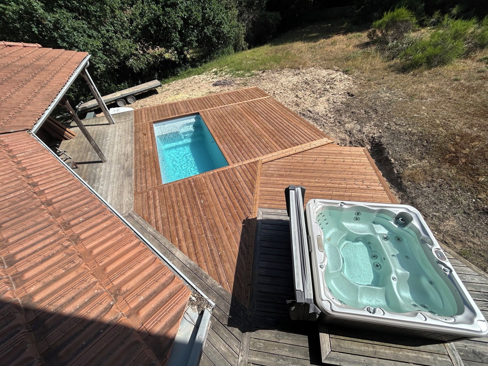 Une terrasse en bois avec un jacuzzi et une piscine.