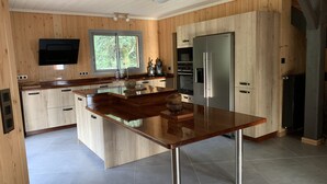 Una cocina moderna con armarios de madera, un refrigerador de acero inoxidable y una isla central.