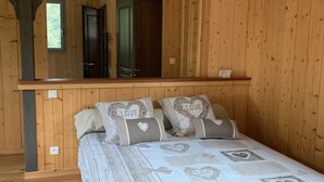 Un dormitorio de madera con cama, almohadas y mesita de noche.