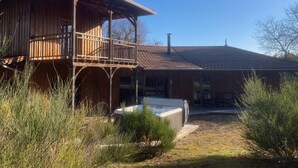 Una cabaña de madera con balcón y jacuzzi en el patio.