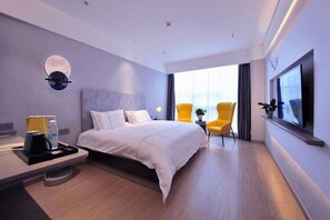 A modern hotel room with a bed, bedside table, chairs, a TV, and a large window. - Magnotel (Rizhao)