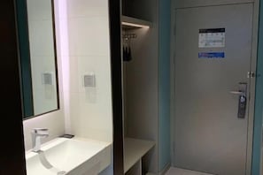 A bathroom with a white sink, a mirror, and a shower area. - Magnotel (Rizhao)