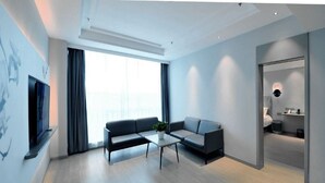 A modern living room with a sofa, coffee table, and a TV mounted on the wall. - Magnotel (Rizhao)