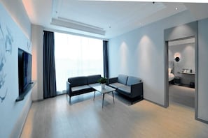 A modern living room with a sofa, coffee table, and a TV mounted on the wall. - Magnotel (Rizhao)