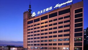 A multi-story hotel building with a prominent sign at the top. - Magnotel (Rizhao)