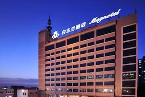 A multi-story hotel building with a prominent sign at the top. - Magnotel (Rizhao)