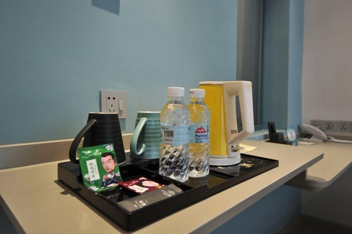 A hotel reception desk with a tray containing a green card, two water bottles, a yellow box, and a black coffee pot.