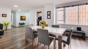 Ein moderner Essbereich mit einem großen Tisch, grauen Stühlen und einem Blumenstrauß.