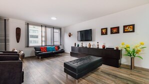 Ein modernes Wohnzimmer mit einer Couch, Hocker und Unterhaltungseinheit.