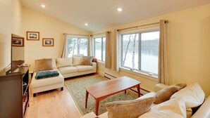 A living room with a sofa, a coffee table, and a TV stand. - Falmouth Vacation Rental On Highland Lake! (Falmouth)