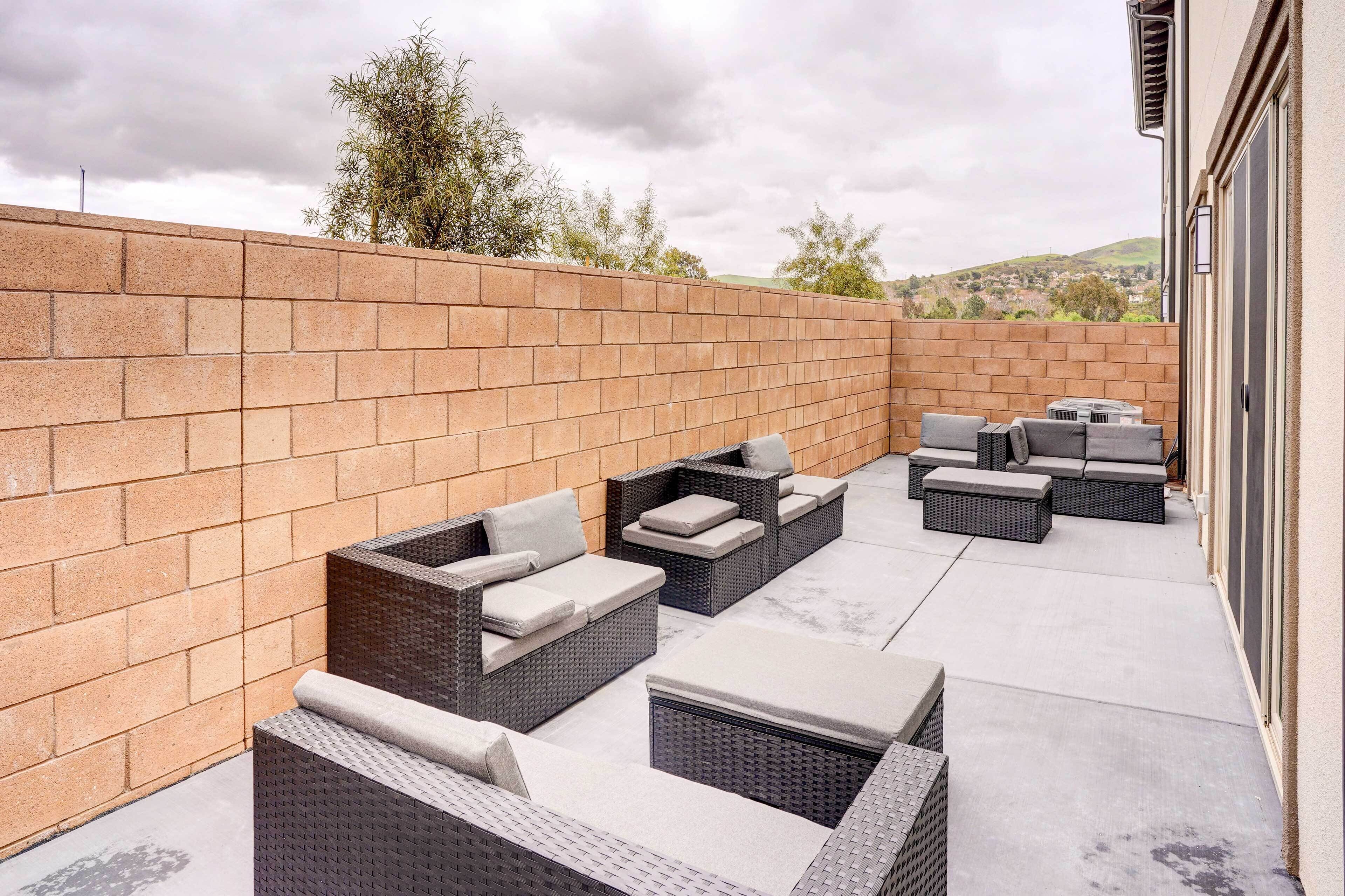 An outdoor patio with wicker furniture, a brick wall, and a view of the landscape.