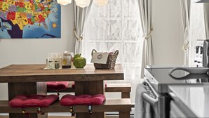 A kitchen with a wooden table, red cushions, a green apple, and a basket with a card. - Historic Waterfront School House (Groton)