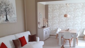 A modern living room with a white sofa, red and brown cushions, a round coffee table, and a dining area with a white table and chairs. - House with swimming pool 2 minutes from Lougratte lake, ideal for families. (Cancon)