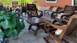 A covered outdoor seating area with wooden furniture and a potted plant.