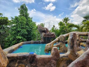 Una piscina con una formación rocosa natural y una cascada.