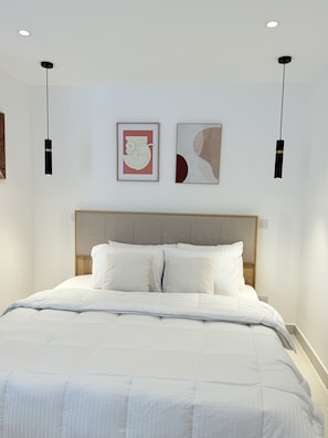 A modern bedroom with a large bed, two wall-mounted pendant lights, and two framed artworks. - Comfortable one bedroom Studio Apartment @ The Lennox Airport Residential Accra (Accra)