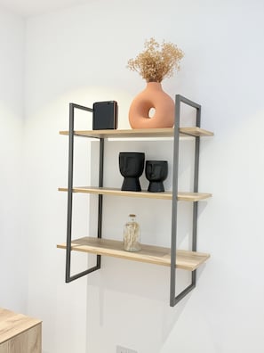 A wall-mounted shelf with a vase, a smartphone, and two black sculptures. - Comfortable one bedroom Studio Apartment @ The Lennox Airport Residential Accra (Accra)