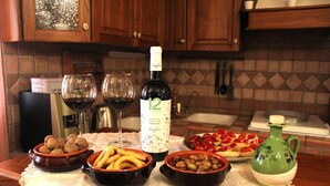 Una encimera de cocina con una botella de vino, copas y diferentes alimentos.