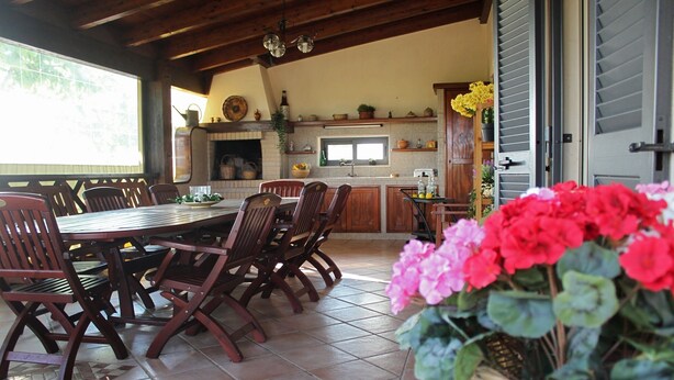 Un comedor con mesa y sillas de madera, una cocina con salpicadero de azulejos y un ventanal grande.