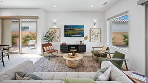 A spacious living room with a large TV, comfortable seating, and a view of the outdoors. - Desert mountain views w/ pool, fire pit & hot tub (La Quinta)