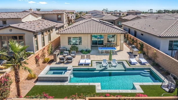 A residential area with a swimming pool, lounge chairs, and a patio area. - Desert mountain views w/ pool, fire pit & hot tub (La Quinta)