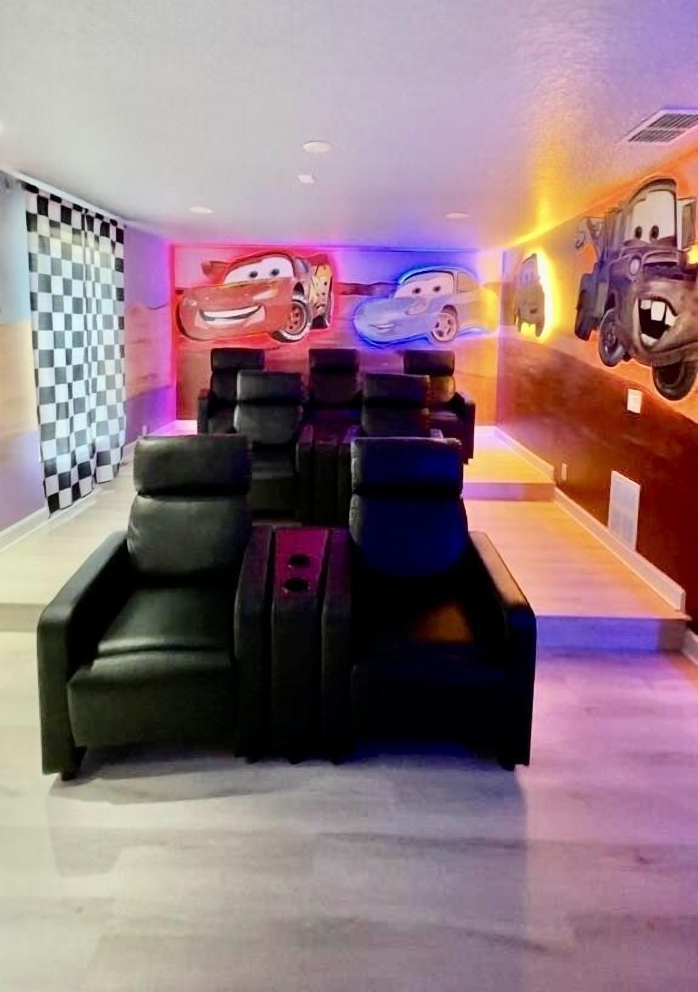 A room with a checkered wall, a wall mural of animated cars, and black cushioned seating.