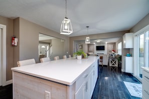 A modern kitchen with a large island, pendant lighting, and a view to the dining area. - 6BR Home w/ Pool - Spooky Nook/MiamiU/KingsIsland (Hamilton)