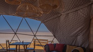 Een gezellig interieur met een tafel, stoelen en een bank, met uitzicht op een strand.