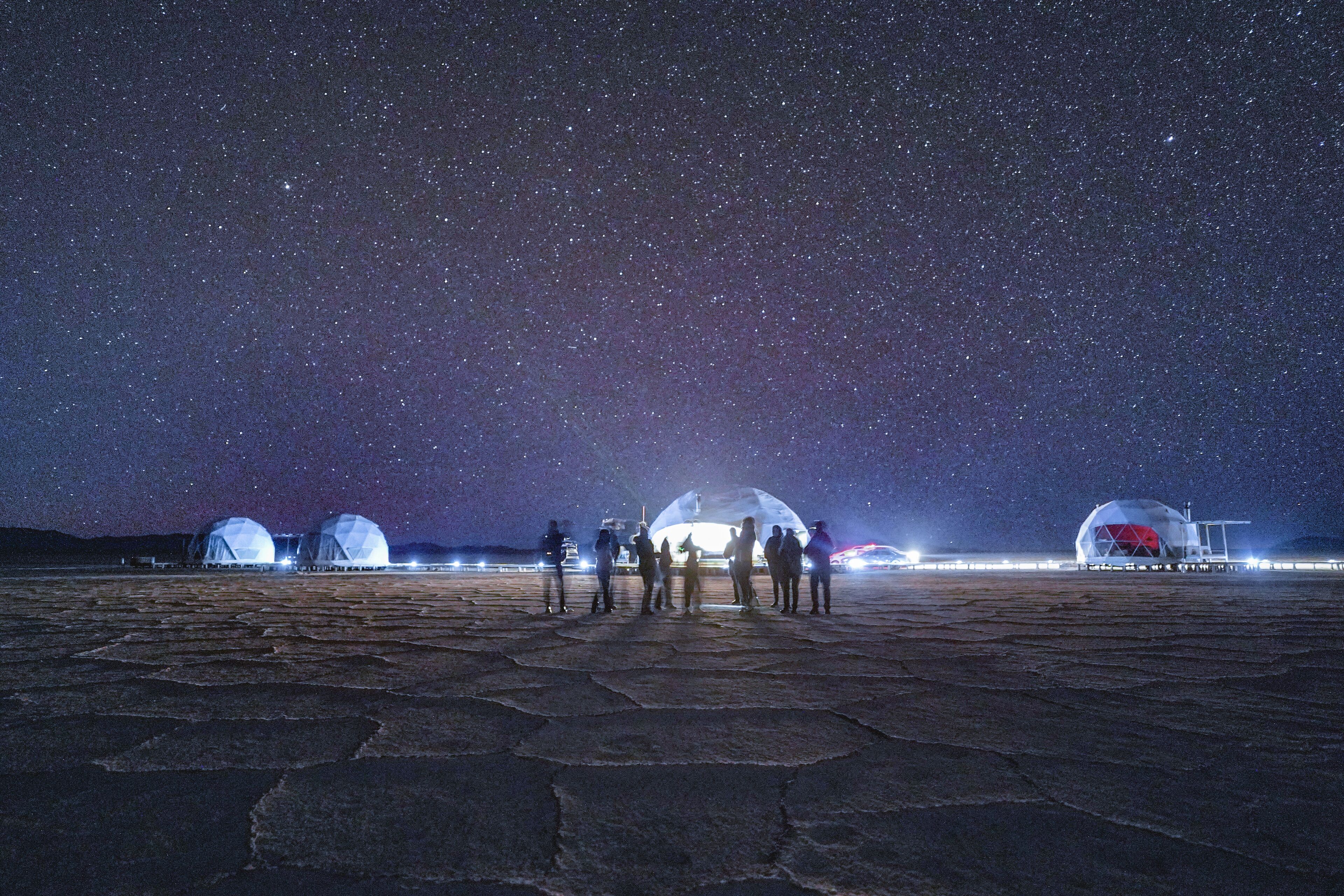 A starry night sky with several domed structures on a flat surface.
