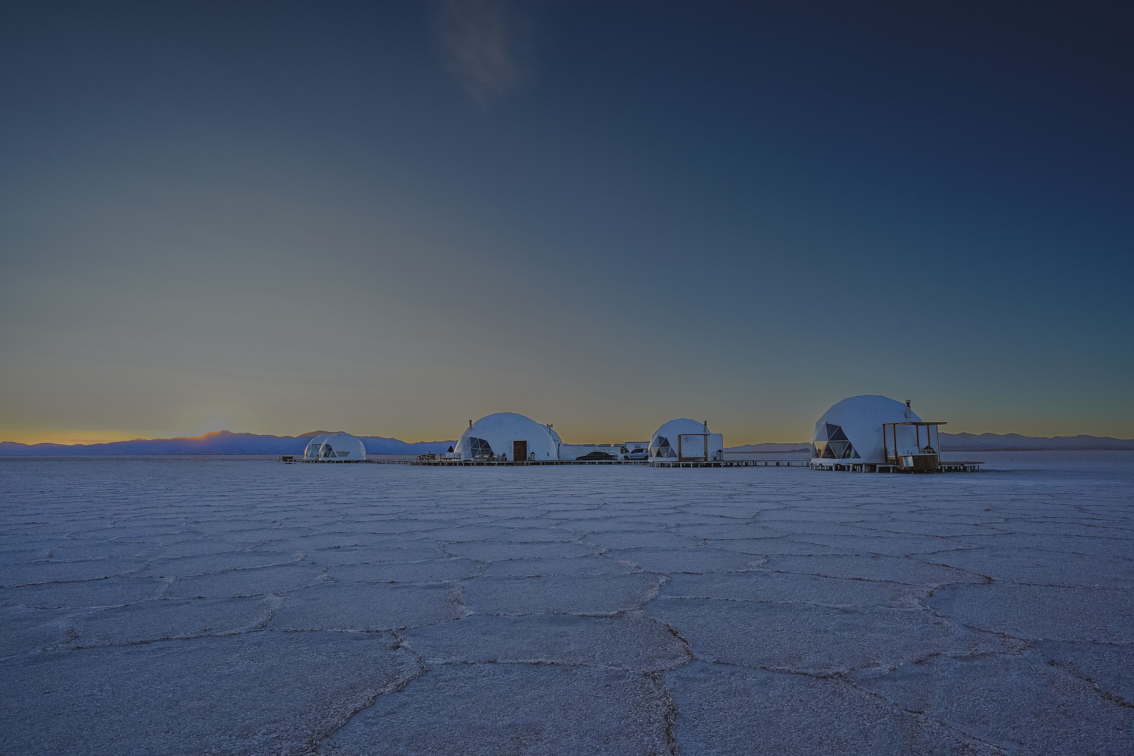 A series of dome-shaped structures in a vast salt flat landscape.