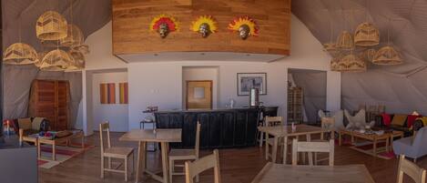 A spacious room with a wooden ceiling, a central bar area, and multiple seating arrangements.