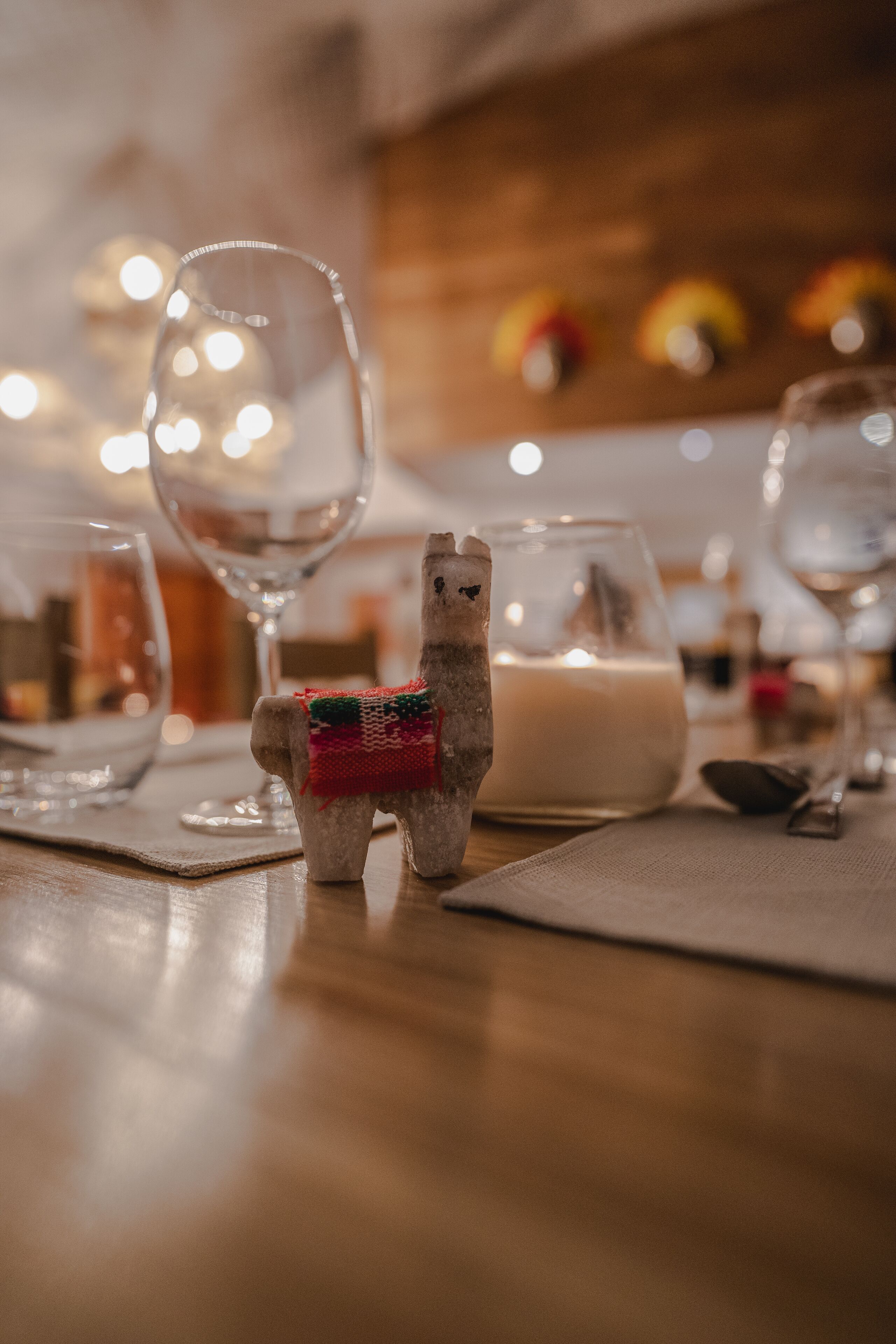 A dining table with clear glassware, a small decorative llama figure, and a candle.