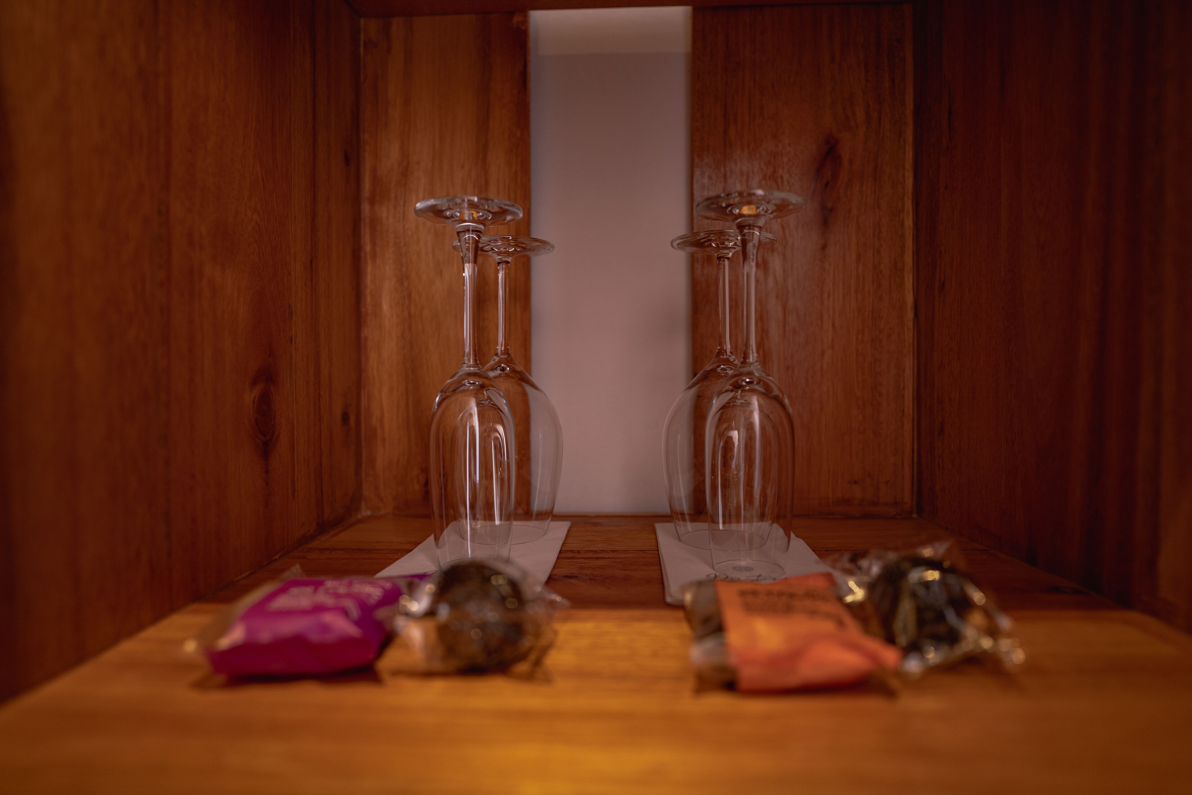 A wooden cabinet with two wine glasses and various small items on the top shelf.