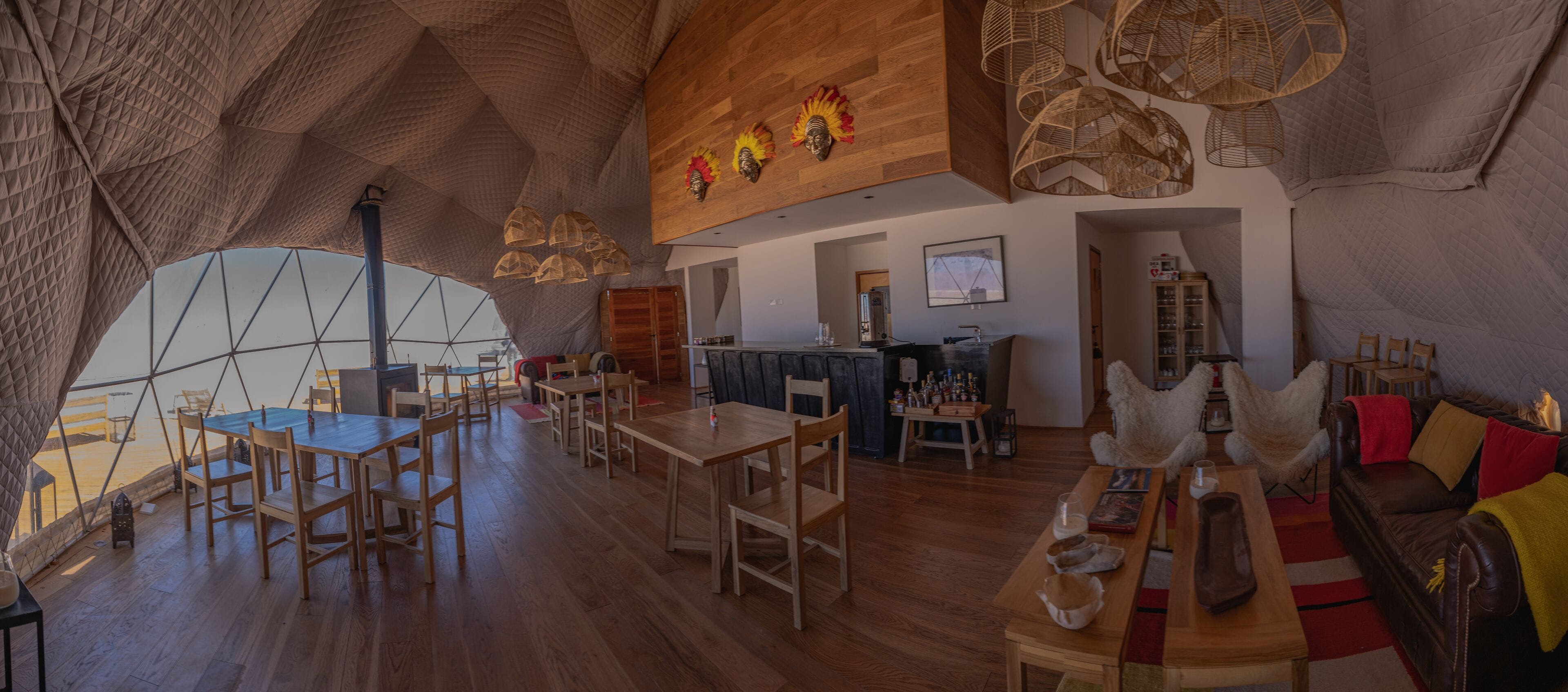 Un interior espacioso con pisos de madera, un comedor con mesas y sillas, una zona de bar y una acogedora sala de estar con cojines.