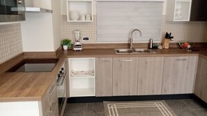 A modern kitchen with wooden cabinets, a built-in sink, and a countertop with a blender. - luxurious apartment 1 bedroom ,1 bathroom with many exciting amenities  (Accra)