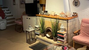 Un soggiorno con divano, tavolino in vetro, televisione, lampada, camino e scala.