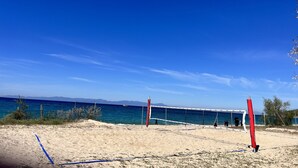 Una spiaggia con un campo da pallavolo, una rete, sabbia e un cielo azzurro limpido.