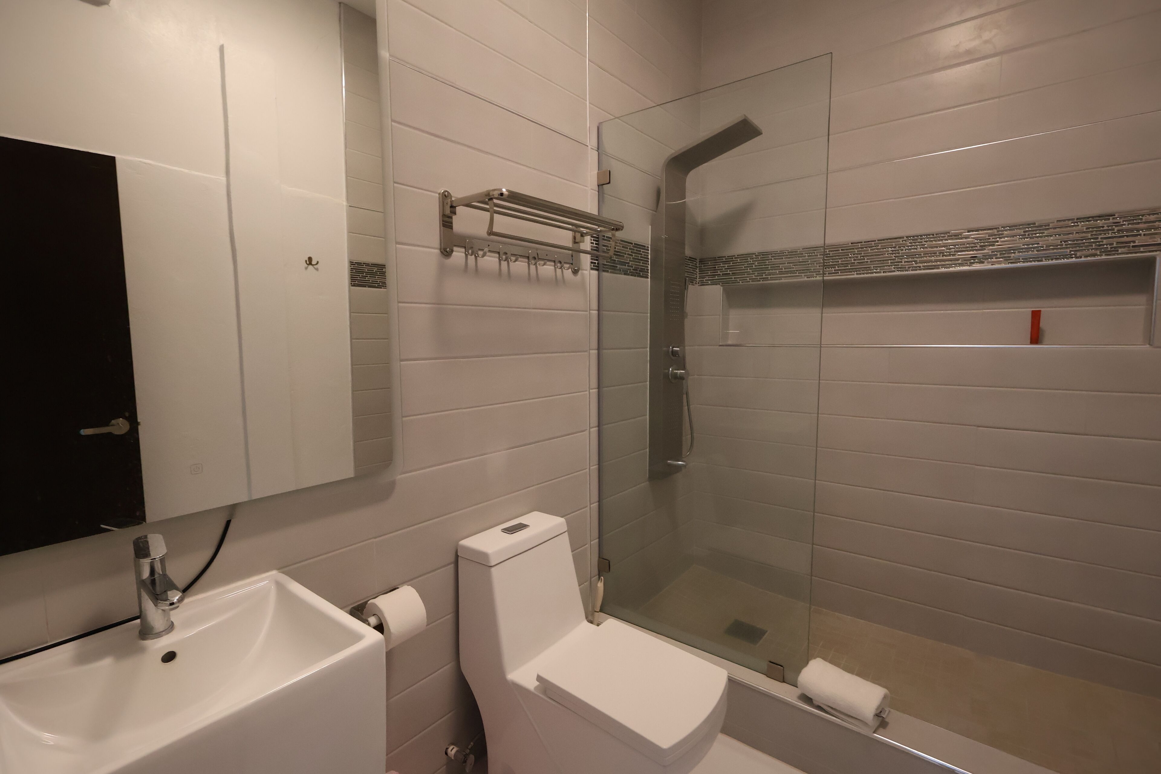 Un baño con lavamanos, inodoro y ducha con mampara de vidrio.