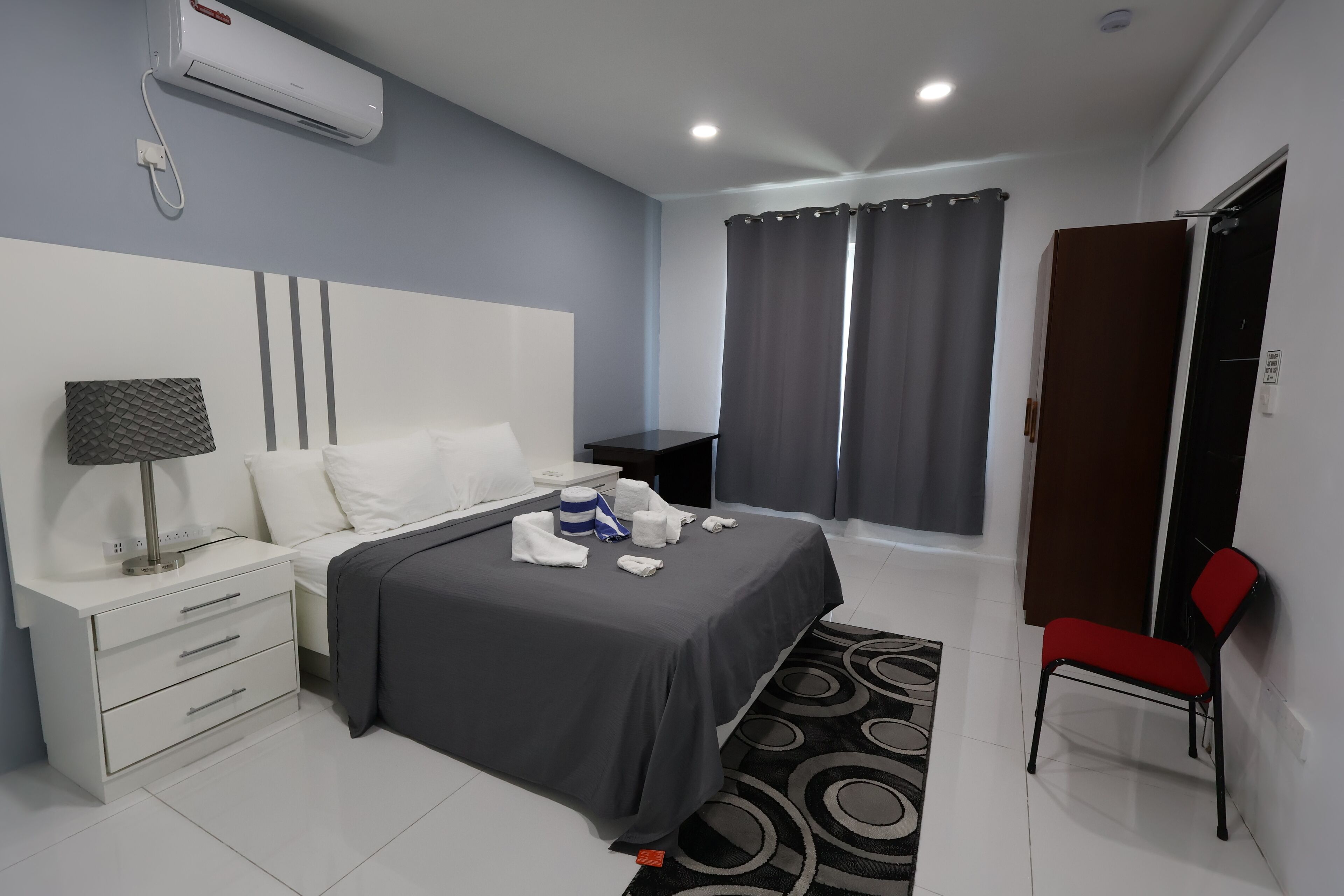 Habitación de hotel con cama, mesita de noche, lámpara y una silla.