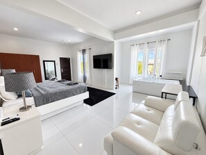 A modern bedroom with a bed, bedside table, and a TV. - PÀRIS Villas 5BD Loft Rodney Bay (Gros Islet)