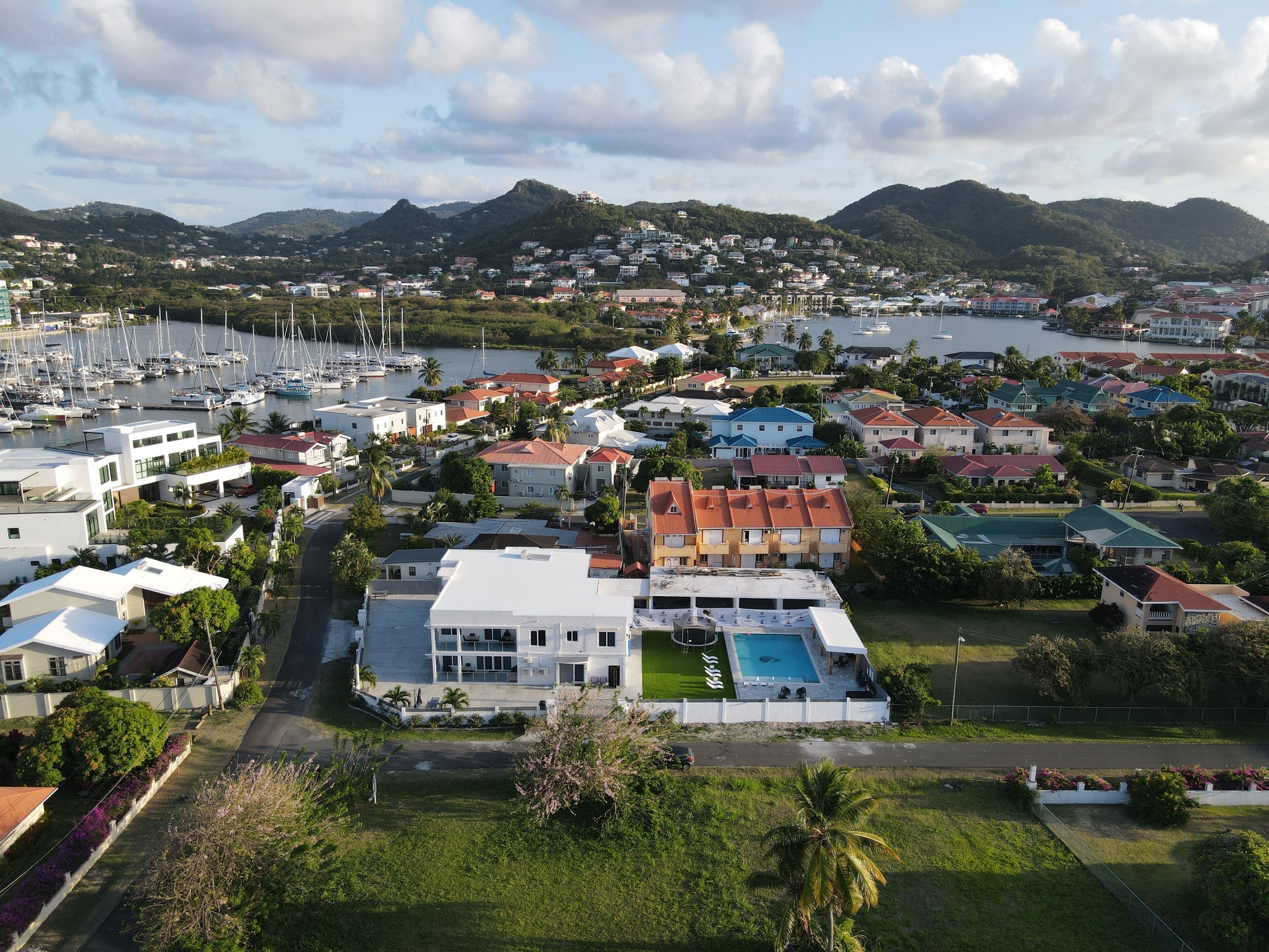 A coastal residential area with houses, a marina, and a large building with a swimming pool.