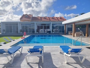 Una piscina al aire libre, sombrillas, sillones reclinables de piscina