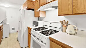A kitchen with white appliances, wooden cabinets, and a kettle labeled "BREW" on the counter. - Cozy Old Town condo + Garage + Patio Steps to Ruston Way! (Tacoma)