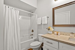 A bathroom with a bathtub, toilet, sink, and a mirror.