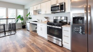 A modern kitchen with stainless steel appliances, white cabinetry, and a wooden floor. - Tacoma Dome condo w Mountn & Bay views + + PRK! (Tacoma)
